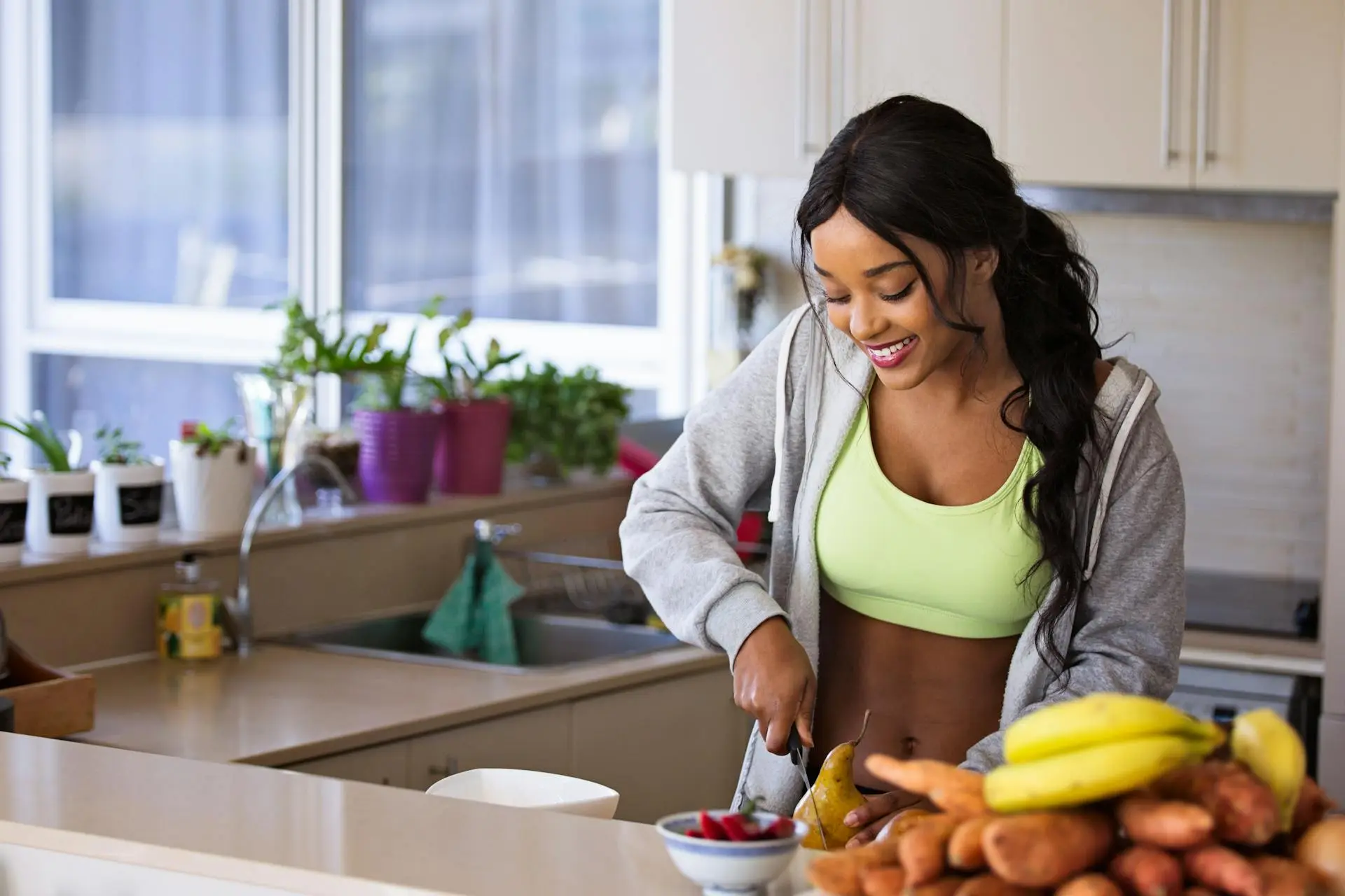 Foto de uma mulher de pele escura cortando frutas em cima de uma mesa